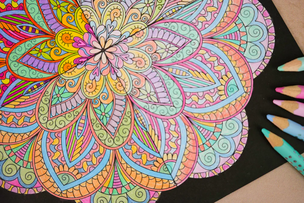 Detailansicht des Mandala-Musters mit pastellfarbenen Buntstiften am Bildrand