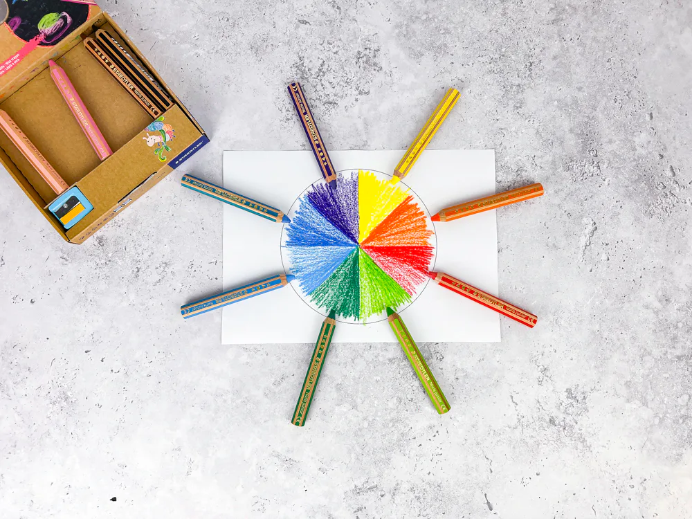 STAEDTLER 3 in 1 Noris junior Buntstifte im Kreis um einen bunten Farbkreis auf Papier