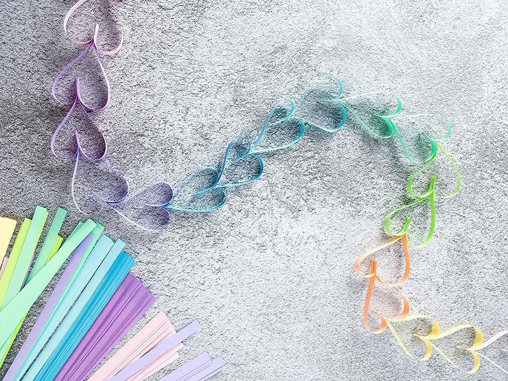 Bunte Herzgirlande aus gefalteten Papierstreifen in Pastellfarben