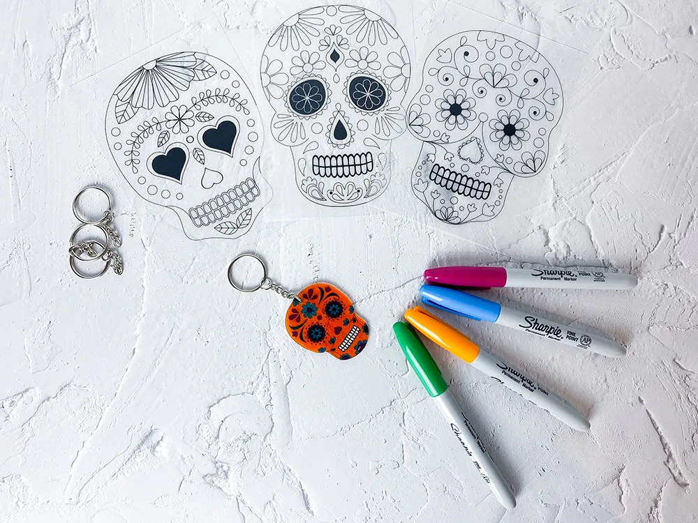 Bunt bemalte Totenkopf-Schrumpffolien und fertiger Schlüsselanhänger mit Sharpies