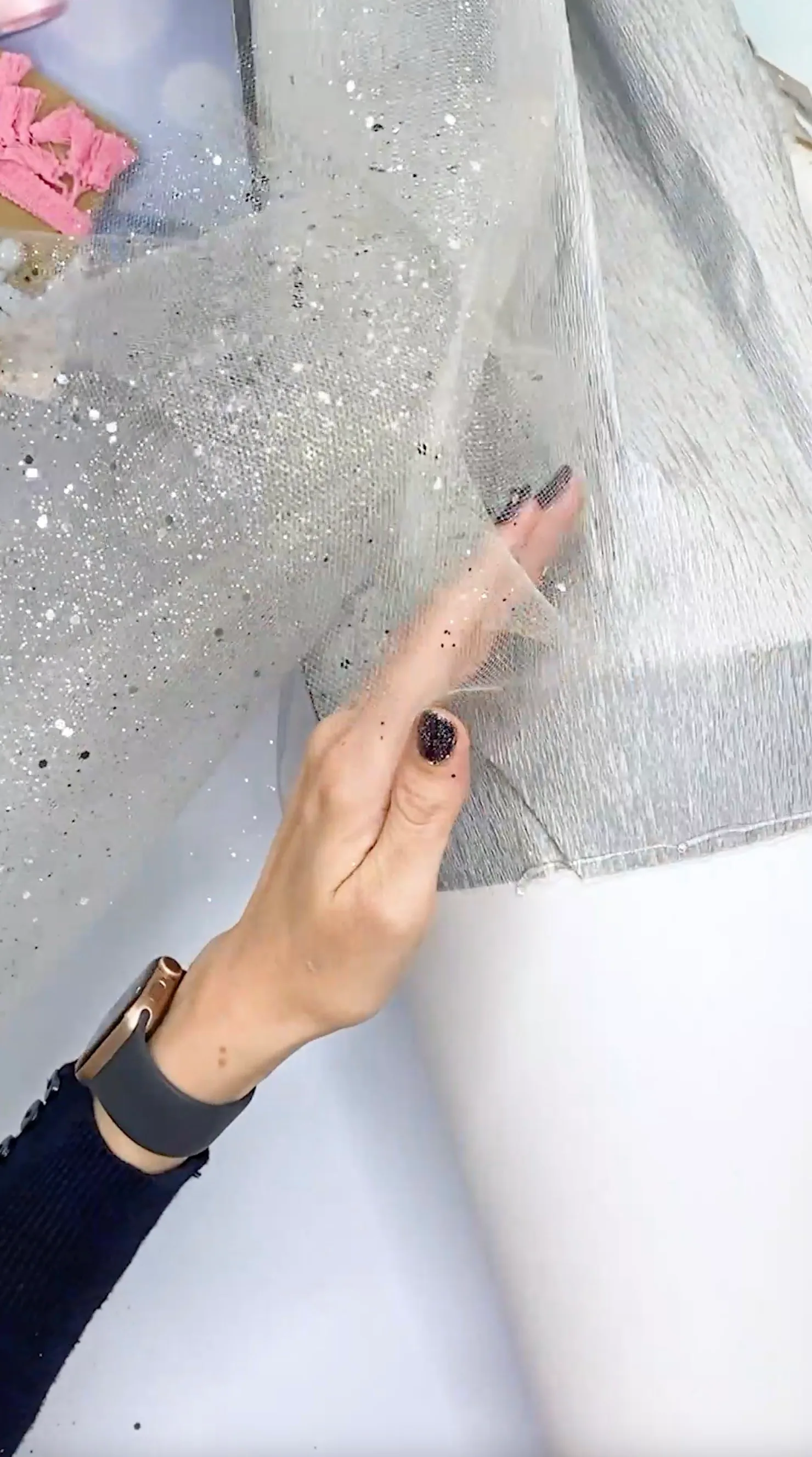 Hand drückt glitzernden Tüll auf die Krepppapier-Spitze der Schultüte