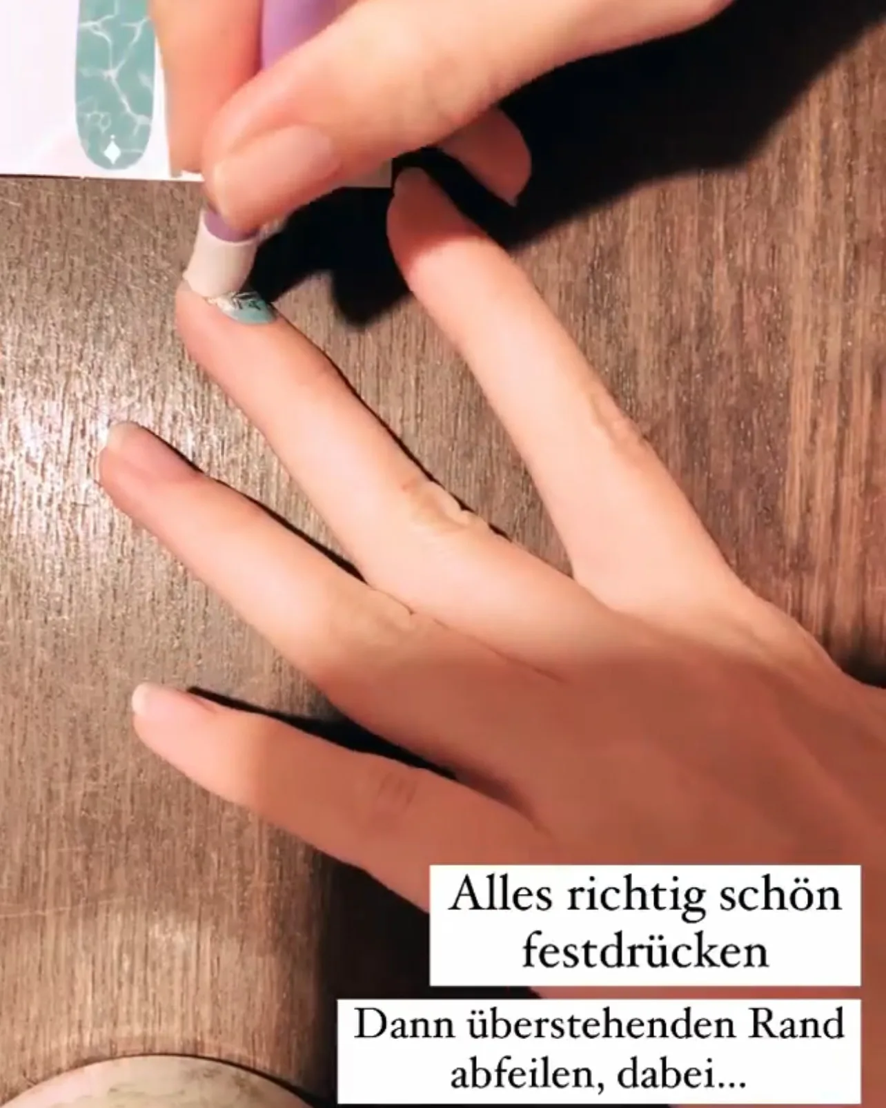 Nagelfolie wird mit einem Silikonstäbchen fest an den Nagel gedrückt