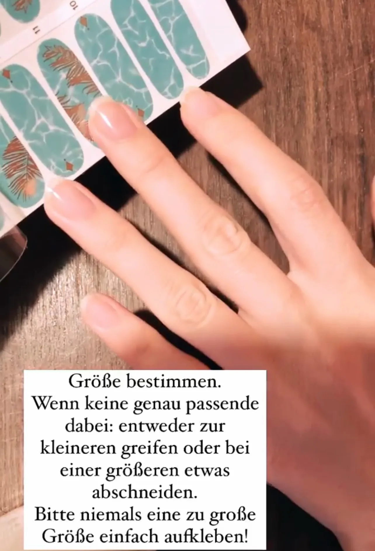 Finger hält Fingerkuppe über den Bogen mit türkiser Nagelfolie zum Größenvergleich