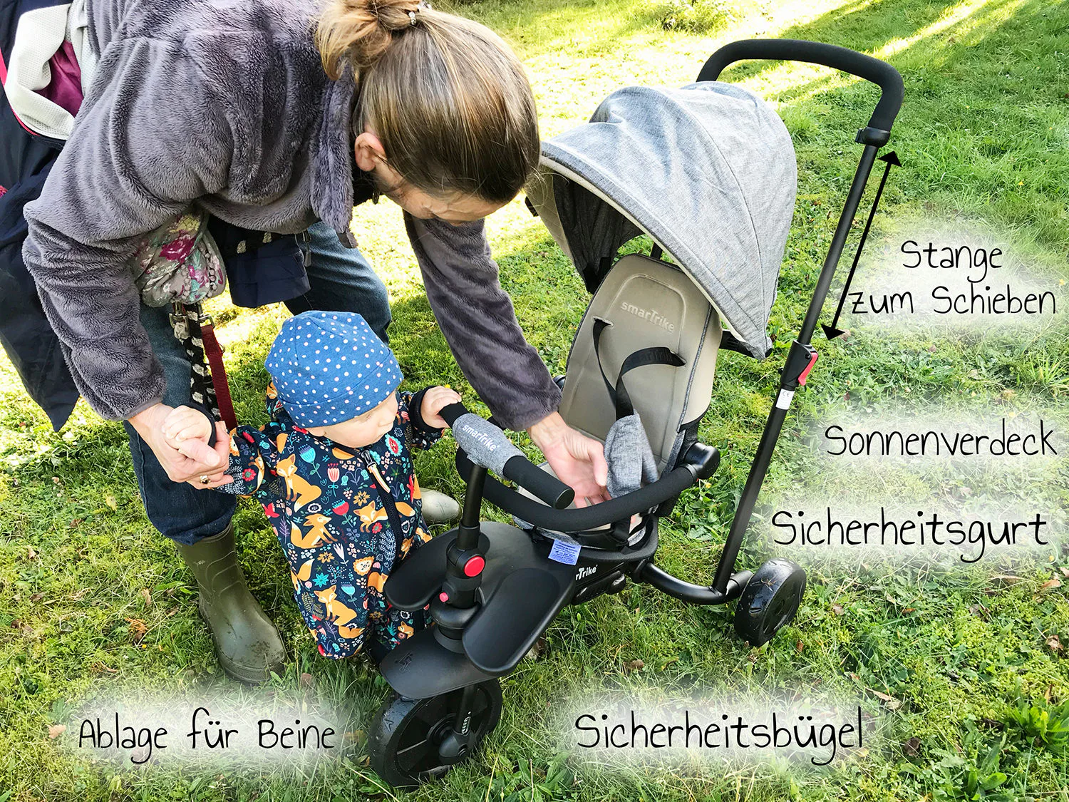 Kleinkind im smarTfold Dreirad mit beschrifteten Details wie Sicherheitsgurt und Sonnenverdeck
