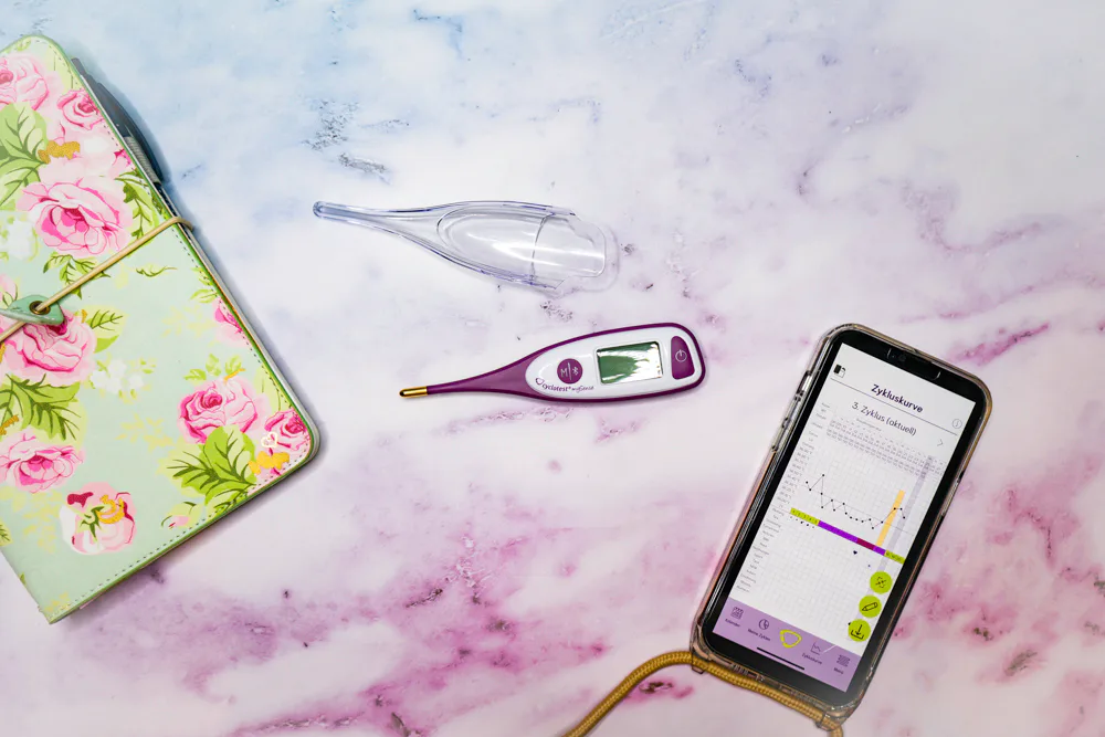 cyclotest mySense Basalthermometer neben einem Smartphone mit Zykluskurve